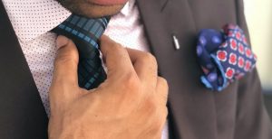 man in formal suit jacket holding his necktie