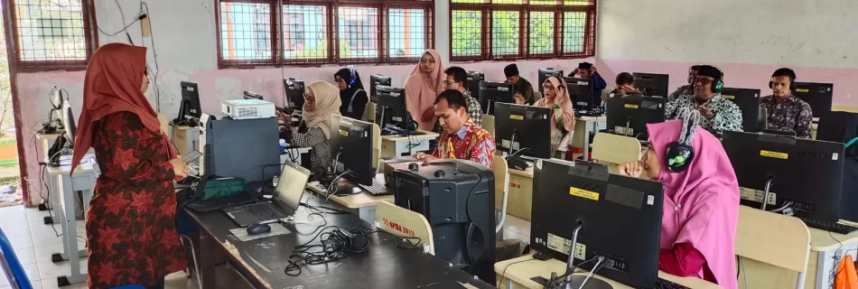 Peserta yang sedang berhadapan dengan komputer mendengarkan pemateri dengan serius