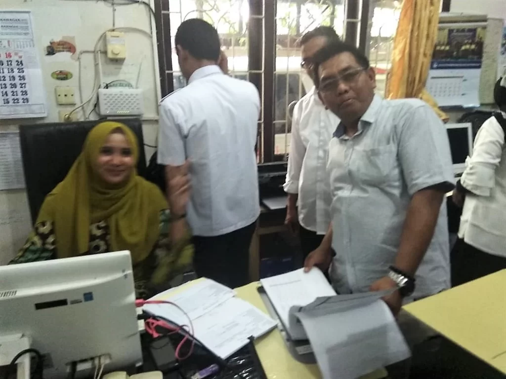 Bu Novi dan Pak Muslim sedang berpose di ruang Tata Usaha